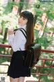 A woman in a white shirt and black skirt holding a black bag.