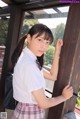 A young woman in a school uniform leaning against a window.