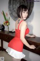 A woman in a red dress standing next to a table.