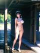 A nude anime girl standing on a dock by the water.