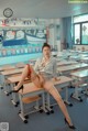 a woman sitting on top of a desk in a classroom