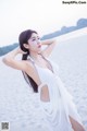 A woman in a white dress standing on a beach.