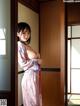 A woman in a pink kimono standing in front of a door.