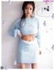 A woman in a blue fuzzy sweater and skirt posing for a magazine.