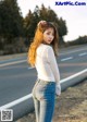 A woman standing on the side of a road with her back to the camera.