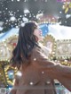 A woman in a fur coat standing in front of a carousel.