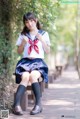 A woman in a school uniform sitting on a bench.