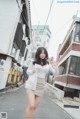 A woman in a white shirt and beige skirt standing on a street.