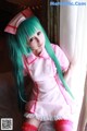 A woman with long green hair wearing a pink nurse outfit.