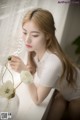 A woman sitting on a window sill next to a vase of flowers.