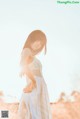 A woman in a white dress standing in a field.