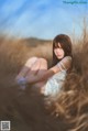 A woman sitting in a field of tall grass.