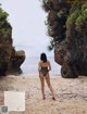 A woman in a bathing suit standing on a beach.