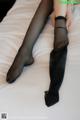 A woman in black stockings is laying on a bed.