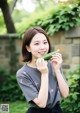 A woman holding a cucumber in front of her face.