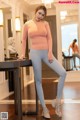 A woman in a pink top and gray leggings posing for a picture.