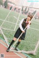 A woman in a school uniform standing next to a soccer goal.