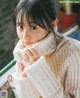 A woman in a white sweater leaning against a window.