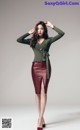 A woman in a green sweater and a red leather skirt.