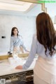 A woman standing in front of a mirror in a bathroom.